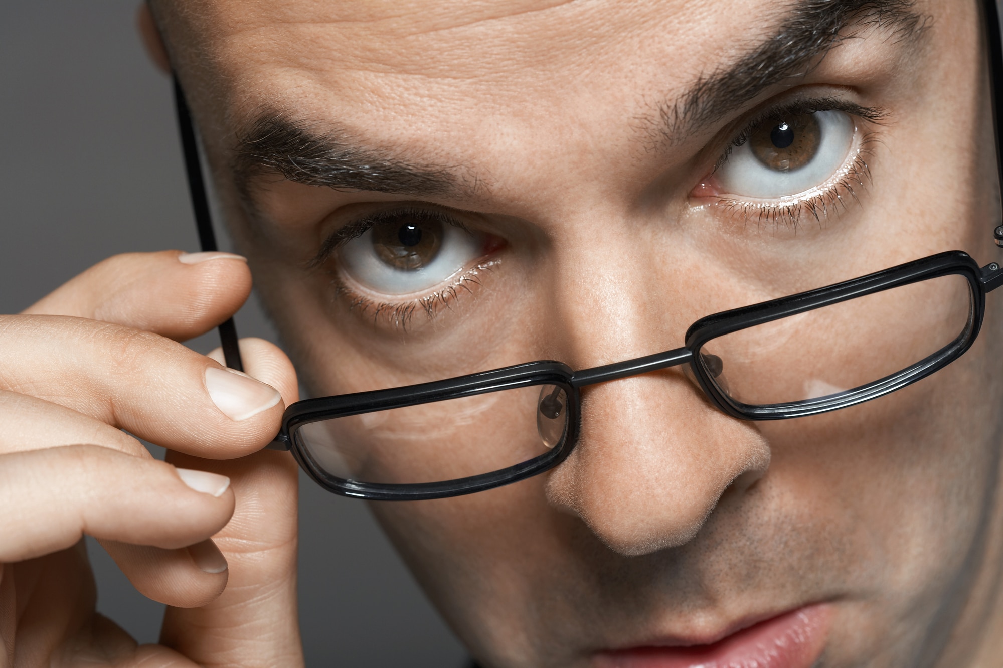 Gros plan d'un homme examinant derrière ses lunettes