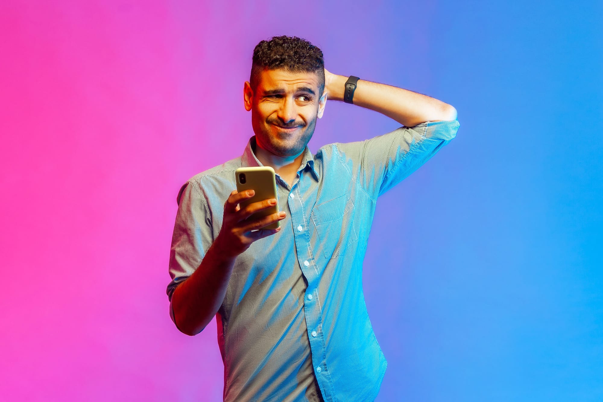 Homme se posant une question en regardant son smartphone